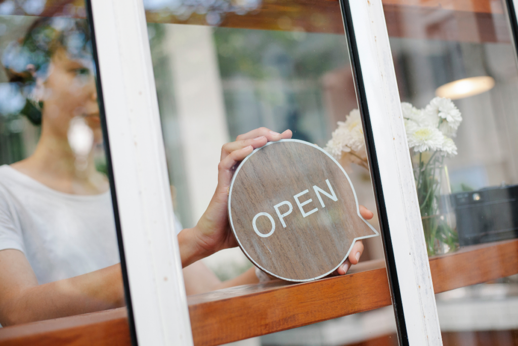 Small business owner putting open sign in front window.